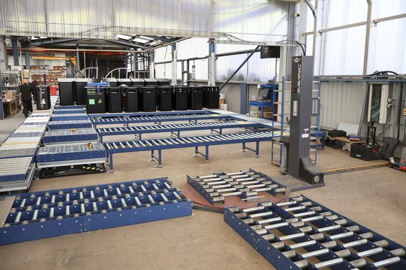Fördersystem für die Stadtmöbelproduktion Industrial conveyor network with roller transfer sections and street furniture products in a manufacturing facility