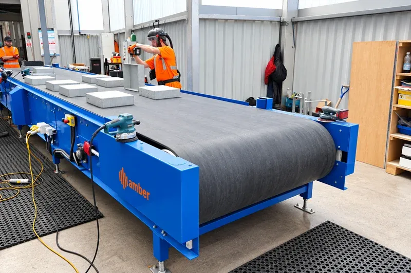 Industrielles Förderband für die Stadtmöbelproduktion Amber Industries industrial belt conveyor transporting concrete components in a manufacturing facility